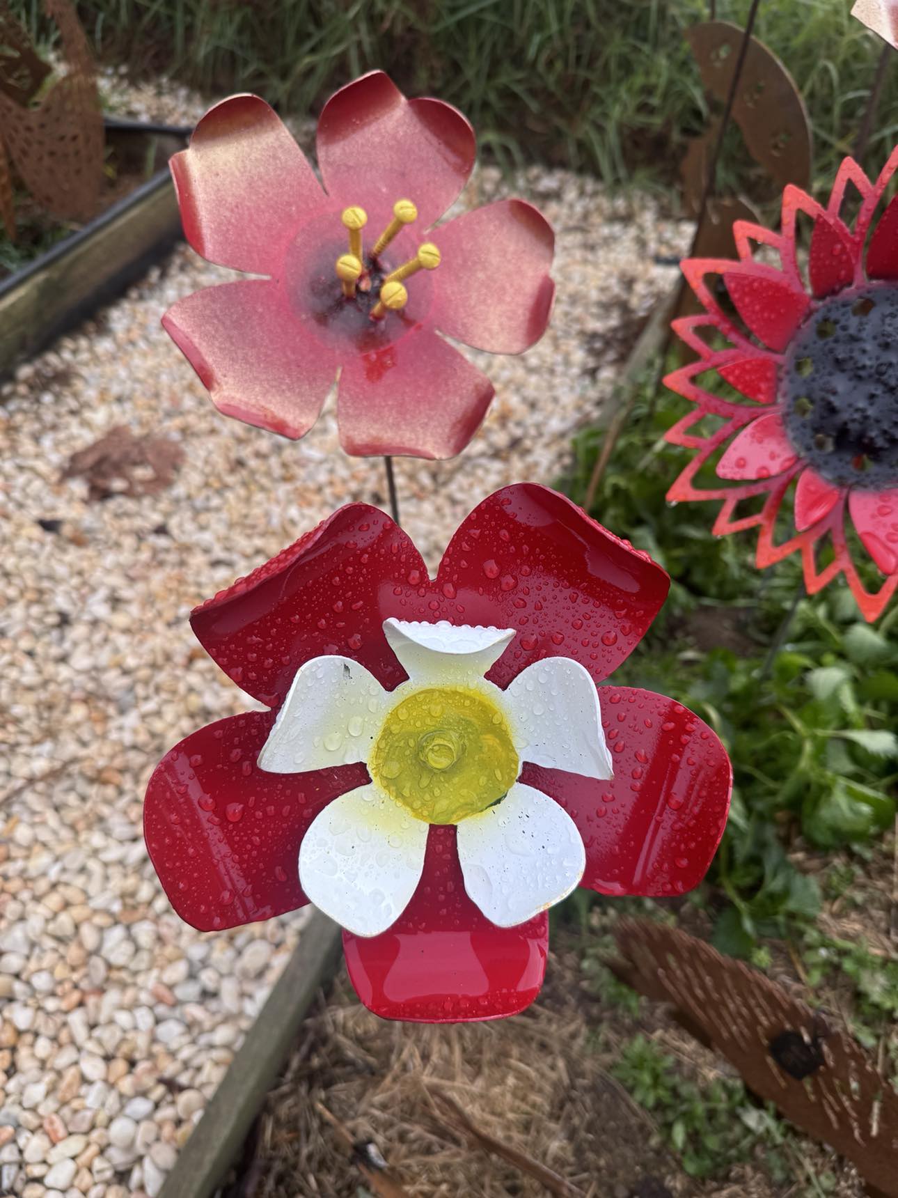 A vibrant metal flower garden featuring striking red and white flowers, showcasing artistic craftsmanship and color contrast.