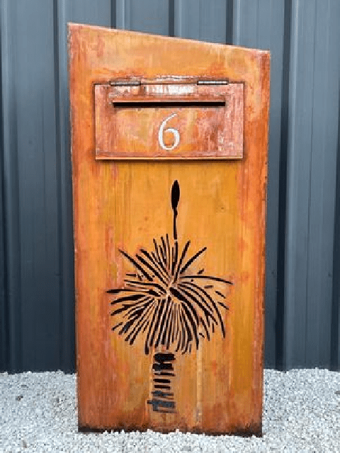 A mailbox adorned with a cow sits amidst lush green grass, creating a whimsical rural scene.