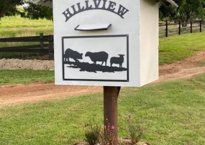 A mailbox adorned with a cow sits amidst lush green grass, creating a whimsical rural scene.