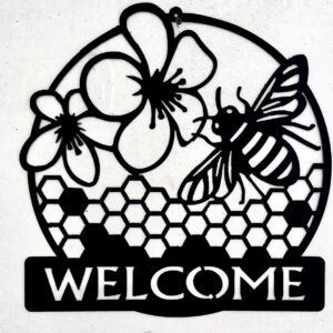 Circular black metal sign with flowers, a bee, honeycomb pattern, and "WELCOME" text.