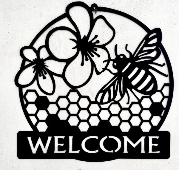 Circular black metal sign with flowers, a bee, honeycomb pattern, and "WELCOME" text.