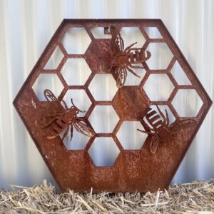 Rusty metal hexagon with bee and honeycomb cutouts, against a corrugated background.