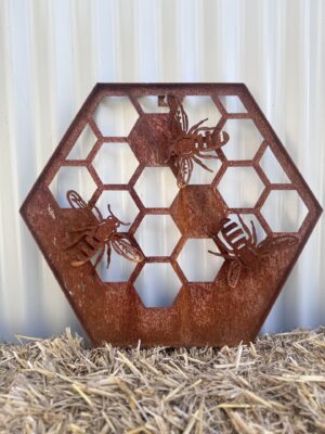 Rusty metal hexagon with bee and honeycomb cutouts, against a corrugated background.