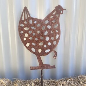 Rustic metal chicken silhouette garden ornament on a straw surface against a corrugated background.