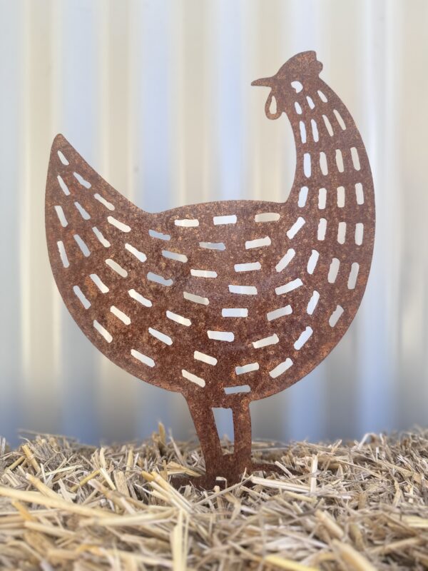 Rustic metal chicken silhouette on straw with a corrugated iron background.