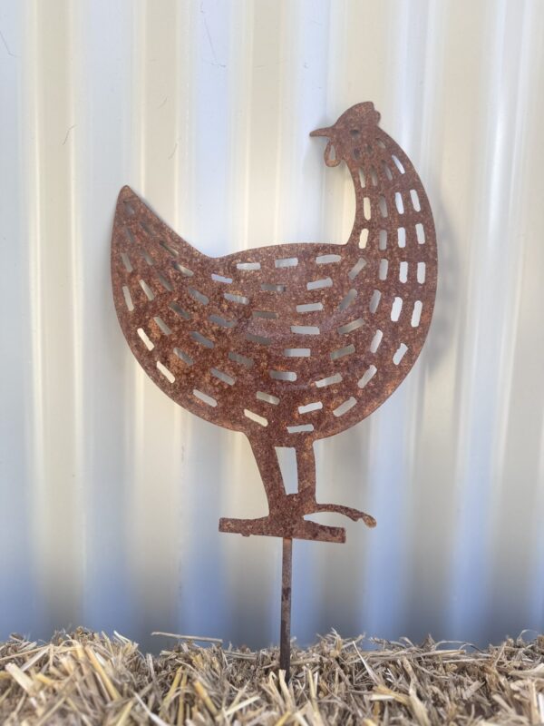 Rusty metal chicken silhouette against a corrugated background, standing on straw.