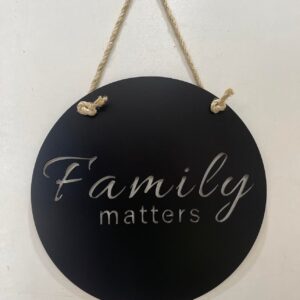 Round black sign with "Family matters" in white script, hanging by a rope.