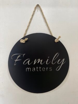 Round black sign with "Family matters" in white script, hanging by a rope.