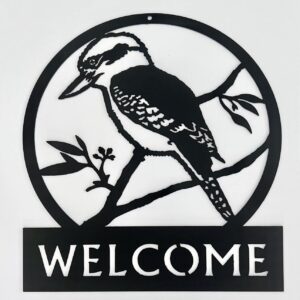 Circular black metal "Welcome" sign with a silhouette of a woodpecker on a branch.