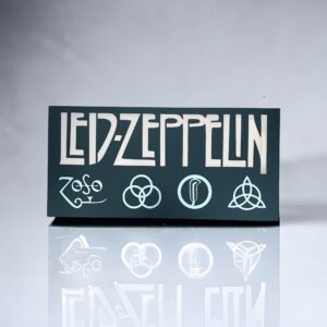 Dark plaque with "Led Zeppelin" text and four symbols, reflected on a glass surface.