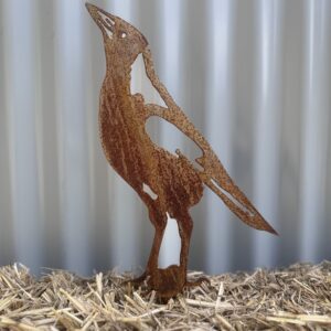 Rusty metal cutout of a penguin on straw, with a corrugated iron background.