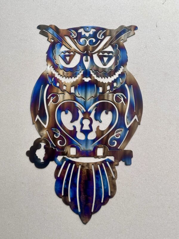 Metallic owl with intricate designs and iridescent colors against a light background.