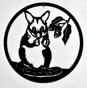 Black metal cut-out of a raccoon with a leafy branch inside a circle, mounted on a wall.