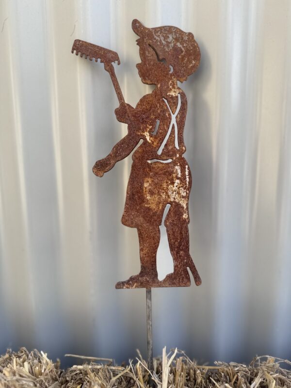 Rusted metal garden silhouette of a girl holding a rake, against a corrugated background.