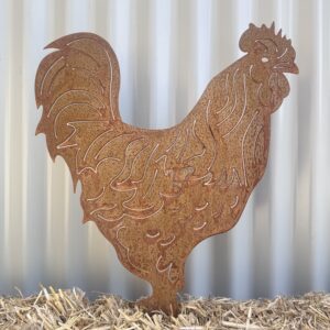 Rustic metal rooster silhouette on straw against a corrugated metal backdrop.