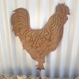 Rustic metal rooster silhouette against a corrugated wall, standing on straw.