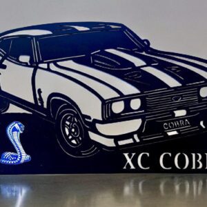 Black silhouette of a classic car with "XC COBRA" text and cobra graphic on reflective surface.