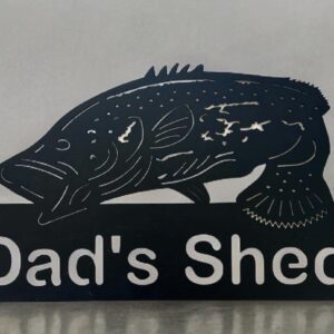 Metal sign with silhouette of a fish and the words "Dad's Shed" against a gray background.