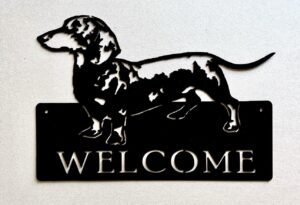 Metal silhouette of a dachshund on a 'WELCOME' sign.