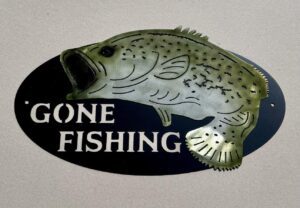 Oval sign with a fish illustration and the words "GONE FISHING" on a dark background.