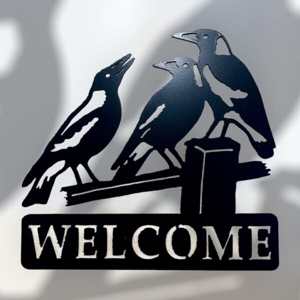 Metal "WELCOME" sign with three silhouette birds perched on it.