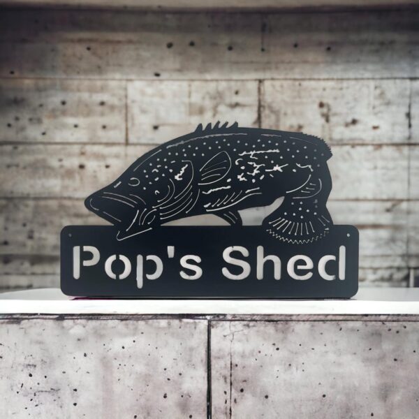 Black silhouette of a fish above "Pop's Shed" text, in front of a wooden wall.