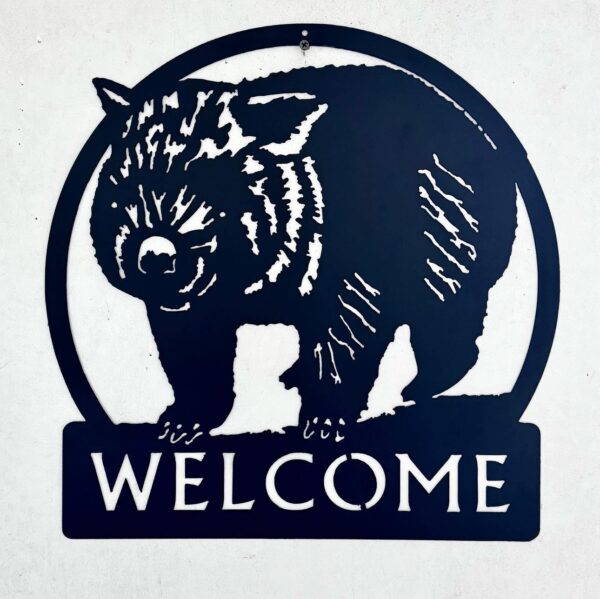 A metal sign featuring a cut-out image of a pig with the word "WELCOME" below it.